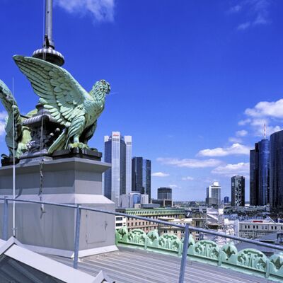 Adlerstatue auf dem Bahnhofsdach des Frankfurter Hauptbahnhofs, im Hintergrund Hochhäuser